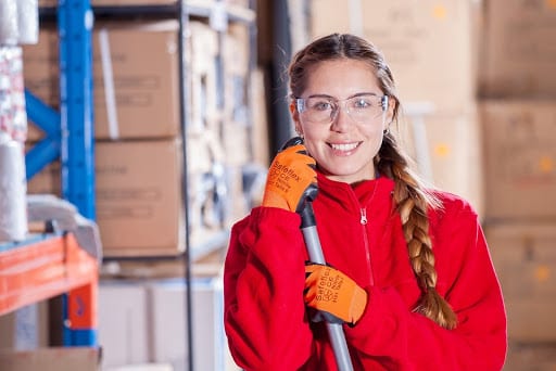 Woman with safety glasses smiling in factory